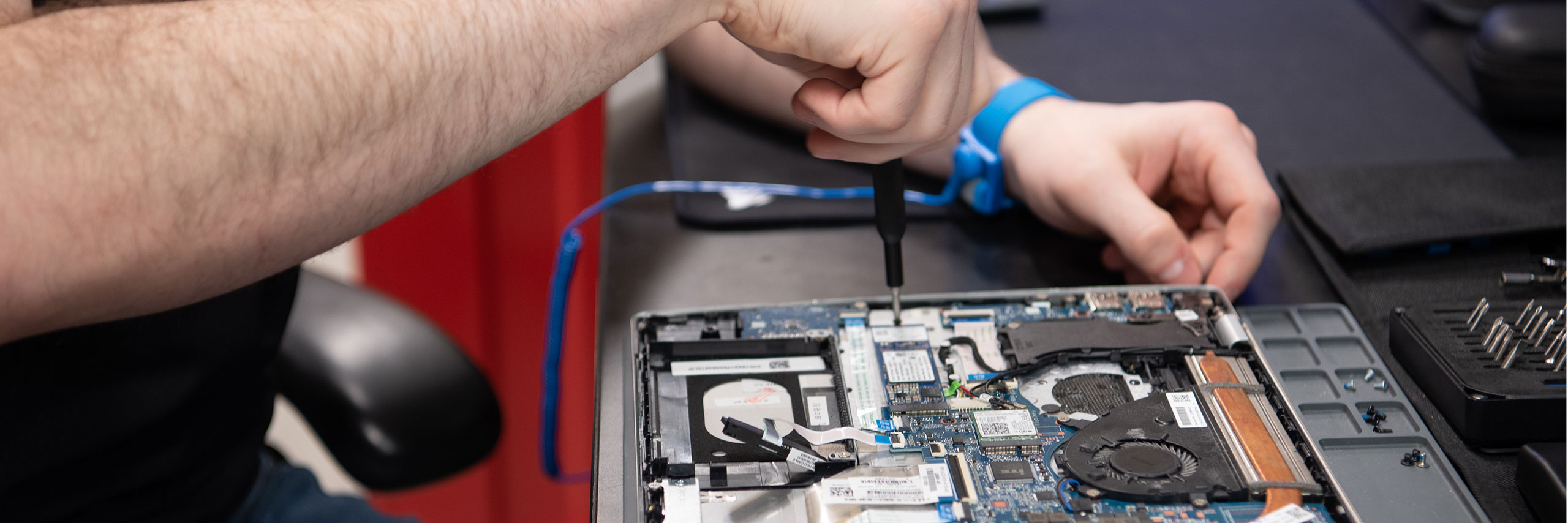 Close-up view of service repairman using a small screwdriver on the internal components of a laptop.
